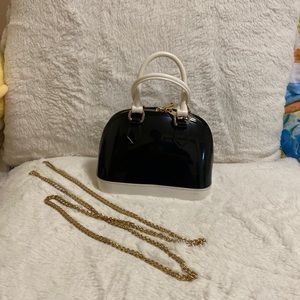 Small crossbody/hand bag with gold toned chain straps.